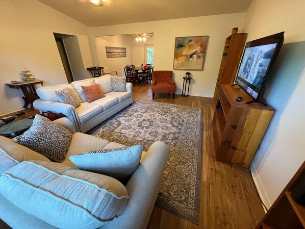 Una sala de estar con un sofá, una mesa de centro, una alfombra, un televisor y un cuadro en la pared.
