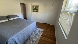 A bedroom with a bed, a ceiling fan, a door, and a window with blinds. - Cozy, Peaceful and Quiet Deerwood Cottage (Lake City)