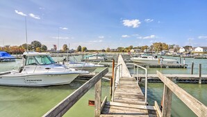 Een jachthaven met liggende boten, houten steigers en huizen op de achtergrond.