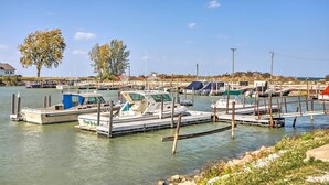 Een jachthaven met diverse boten afgemeerd, een heldere lucht en enkele bomen op de achtergrond.