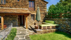 Une maison en pierre dotée d’un patio couvert, d’un espace extérieur aménagé avec des sièges et d’un mur en pierre.