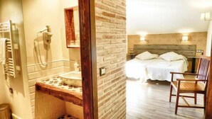 Une chambre d’hôtel avec un lit à cadre en bois, une chaise en bois, un lavabo avec un miroir et un téléphone.