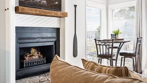 A cozy living room with a fireplace, a television mounted above it, and a dining area with a table and chairs. - The Lucky Minnow  • Pools, Hot Tub, Deck, Grill (Village of Four Seasons)