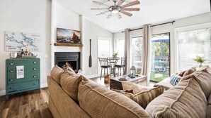 A living room with a fireplace, a dining area, and a large window with a view. - The Lucky Minnow  • Pools, Hot Tub, Deck, Grill (Village of Four Seasons)