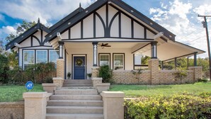 A two-story house with a front porch, a brick facade, and a blue door. - Beautiful 1930s Mineral Wells Home, Near Downtown! (Mineral Welss)