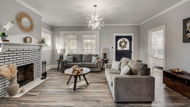 A living room with a fireplace, two sofas, a coffee table, and a chandelier. - Beautiful 1930s Mineral Wells Home, Near Downtown! (Mineral Welss)