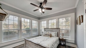 A bedroom with a bed, a ceiling fan, and large windows with blinds. - Beautiful 1930s Mineral Wells Home, Near Downtown! (Mineral Welss)