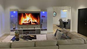A modern living room with a flat-screen TV, a fireplace, a sofa, and a dining area. - The White House TCI Guests house (The Bight Settlement)