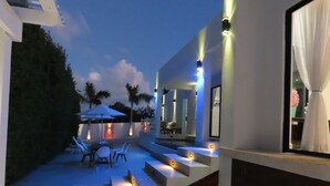 A modern outdoor patio with steps leading to a covered seating area, palm trees, and ambient lighting. - The White House TCI Guests house (The Bight Settlement)