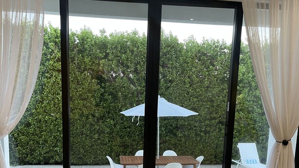 A room with a large sliding glass door leading to an outdoor area with a pool, a table, and chairs. - The White House TCI Guests house (The Bight Settlement)
