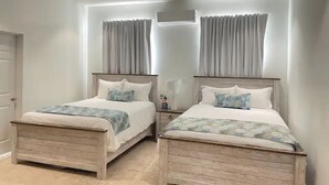 A bedroom with two wooden beds, a nightstand, and a wall-mounted air conditioner. - The White House TCI Guests house (The Bight Settlement)