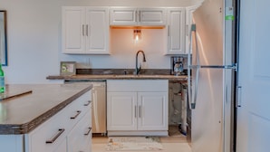 A modern kitchen with white cabinetry, a stainless steel refrigerator, and a built-in oven.