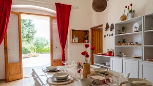 A dining area with a table set for four, a wooden door, and a view of greenery outside. - Amazing Villa with Private Pool in Monopoli (Cozzana)