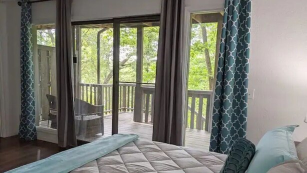 Un dormitorio con una cama grande, vistas a un balcón y una silla afuera.