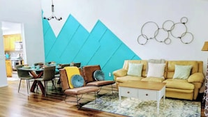 Una sala de estar moderna con un sofá, sillas y una mesa de comedor.