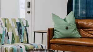 Una sala de estar con un sofá estampado, un sofá de cuero, una mesita con un cuenco y un tapete estampado.