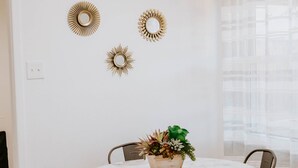 Un comedor con una mesa redonda, cuatro sillas y una planta en maceta sobre la mesa.