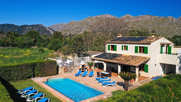 Une villa avec piscine, des volets verts et des panneaux solaires.