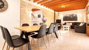 Un coin repas avec une table et des chaises en bois, un mur en pierre, et un salon avec un canapé et un tableau.