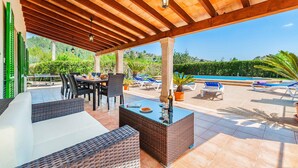 Un espace extérieur aménagé en terrasse, avec des meubles en osier, une piscine et une vue sur le paysage environnant.