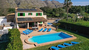 Une villa avec piscine, des volets verts et des panneaux solaires.