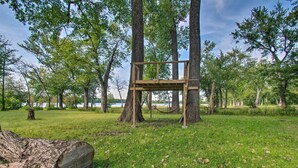 A wooden platform in a forested area with a lake in the background. - Cozy Riverfront Getaway: Fishing On-Site! (Lacon)