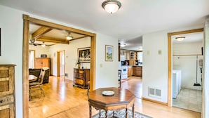 A spacious living room with hardwood floors, a wooden dining table, and a large rug.