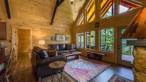 Ein gemütliches Blockhaus-Interieur mit Ledersofa, Couchtisch und farbenfrohem Teppich.