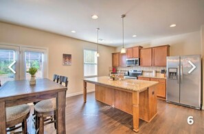 Enjoy cooking in this well-equipped kitchen with a central island, stainless steel appliances, and ample dining space.