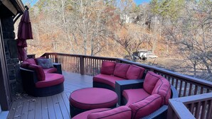 A wooden deck with outdoor furniture and a view of trees.
