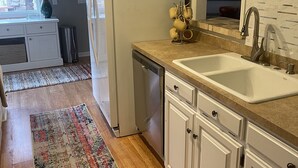 A kitchen with white cabinets, a sink, and a refrigerator.