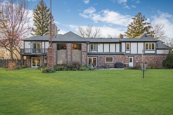 A two-story house with a brick facade, a balcony, and a well-maintained lawn.