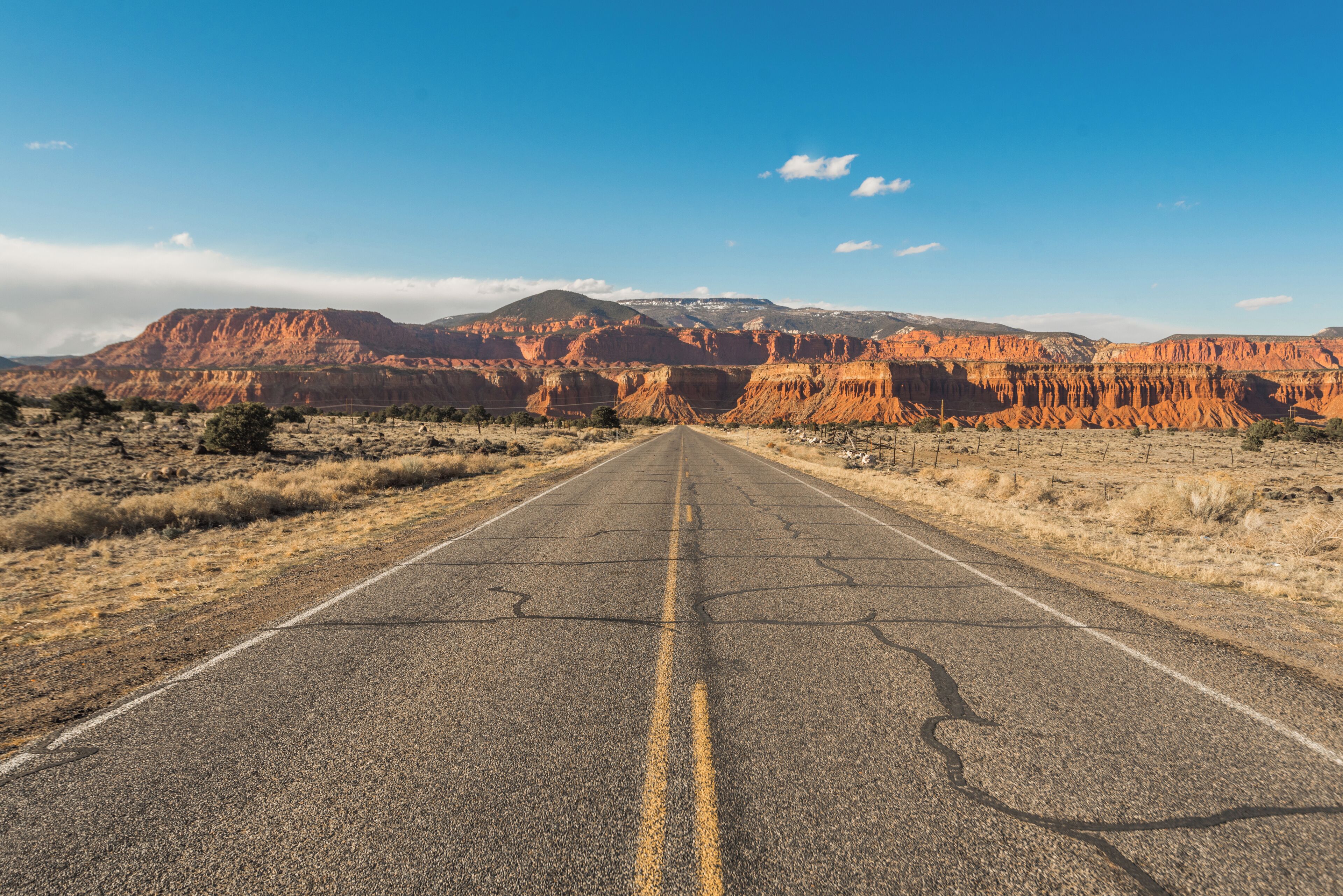 A straight road leading towards a mountainous landscape with a clear sky.