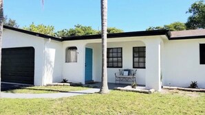 Une maison de plain-pied avec un garage, une porte d’entrée et un petit porche doté d’un banc.