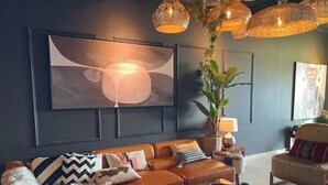 A modern living room with a leather sofa, a coffee table, and a large abstract painting on the wall. - A lavish hidden gem in the heart of Dubai marina. (Dubai)