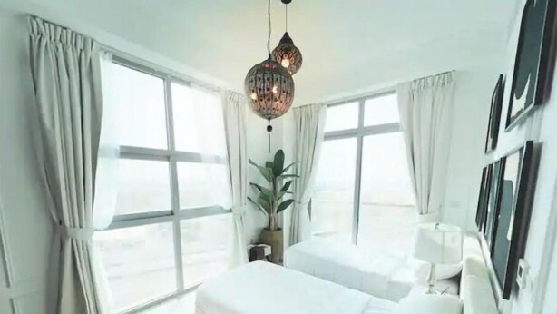 A modern bedroom with a large bed, two windows, and a hanging light fixture. - A lavish hidden gem in the heart of Dubai marina. (Dubai)