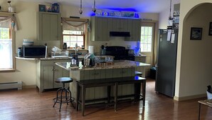 A spacious kitchen with a central island, wooden flooring, and a ceiling fan. - 20min from Acadia Retreat With Internet & Gaming Amenities (Hancock)