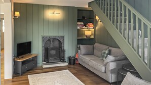 A living room with a fireplace, a sofa, a TV, and a staircase.