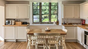A modern kitchen with white cabinetry, a wooden dining table, and four chairs.