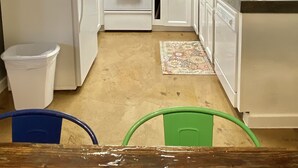 Una cocina compacta con armarios blancos, un microondas, estufa y lavabo.