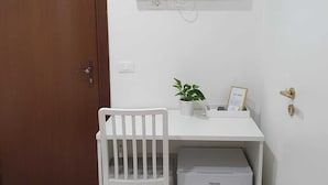 A small, clean room with a white desk, a chair, a television mounted on the wall, and a small white storage unit. - Affittacamere Dianir (Rome)