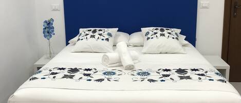 A neatly made bed with a blue headboard, white bedding, and decorative pillows.