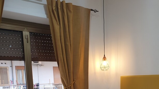 A neatly made bed with a white pillow and a mustard-colored pillow, a rolled white towel, and a brown throw blanket. - Affittacamere Dianir (Rome)