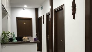 A hotel reception area with a reception desk, a sofa with floral cushions, and a wall-mounted decorative headpiece. - Affittacamere Dianir (Rome)