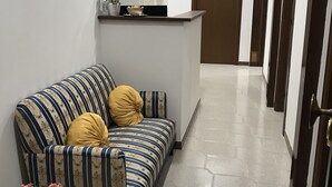 A hallway with a striped sofa, a potted plant, and a reception desk. - Affittacamere Dianir (Rome)