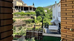 A view from a balcony overlooking a vineyard and a hillside with buildings.