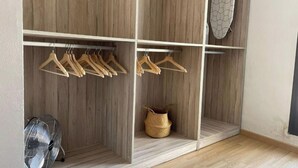 A walk-in closet with wooden paneling, a hanging rack with wooden hangers, a woven basket, and a ceiling fan.