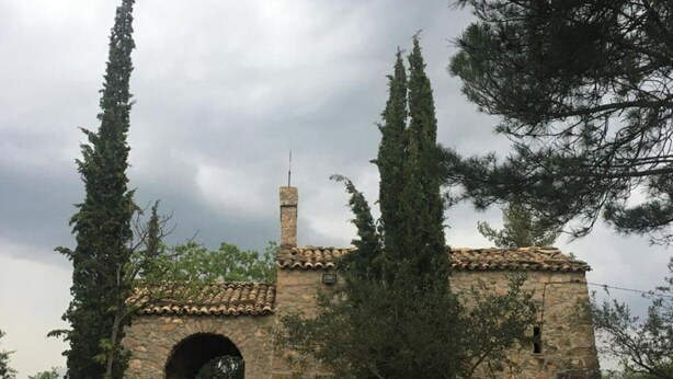 A stone building with a tiled roof and an arched entrance.