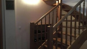 A wooden staircase with a built-in wine rack, leading to a landing with a light fixture.