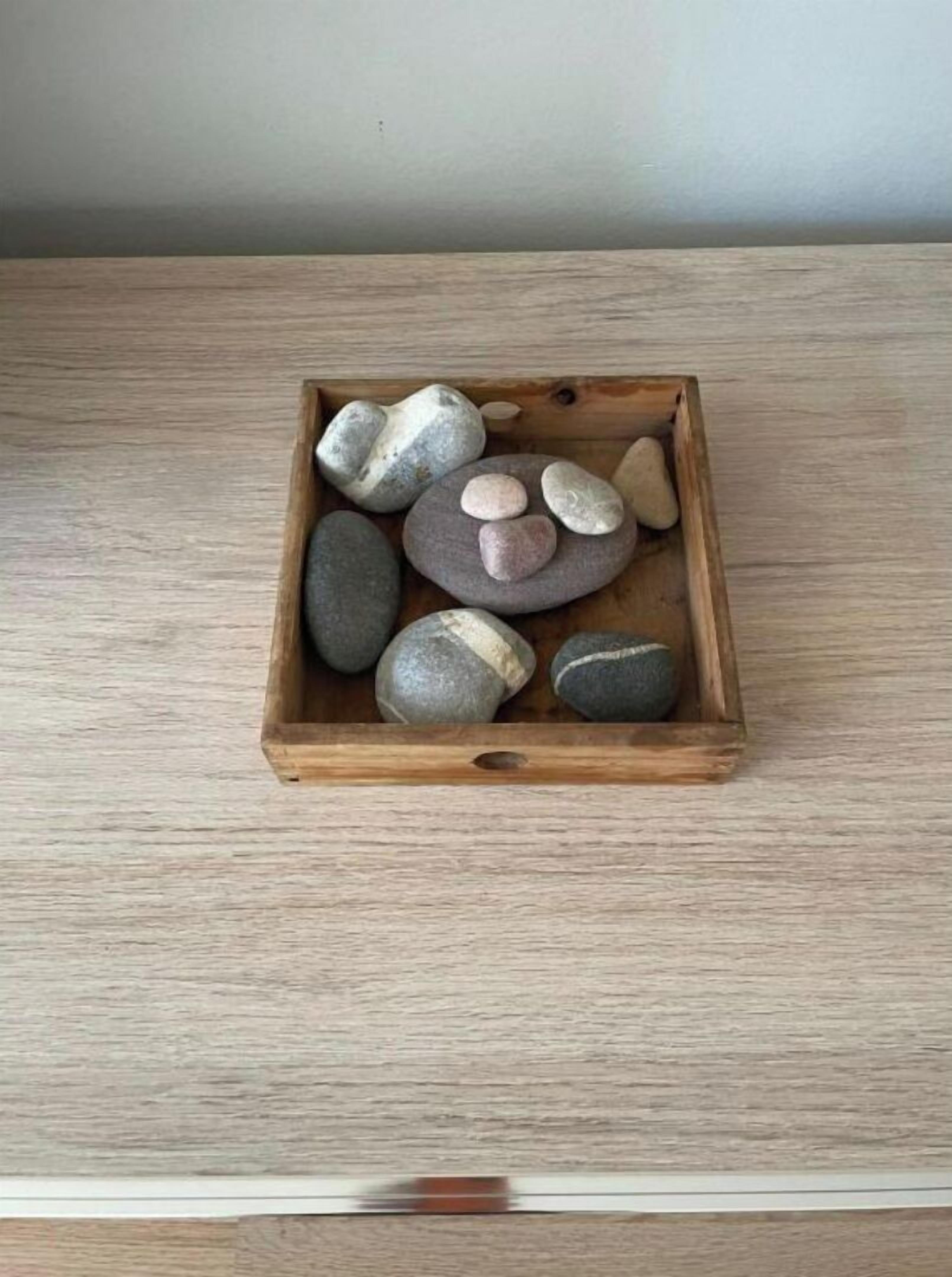 Una bandeja de madera con varias piedras lisas de distintos tamaños y formas.